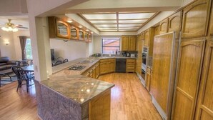 A spacious kitchen with wooden cabinets, a granite island, and a large window providing natural light. - 569 Lucerne 4 Bedroom Home by RedAwning (South Lake Tahoe)