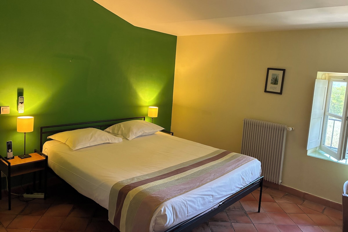 Une chambre avec un lit, deux lampes de chevet, un radiateur et une fenêtre.