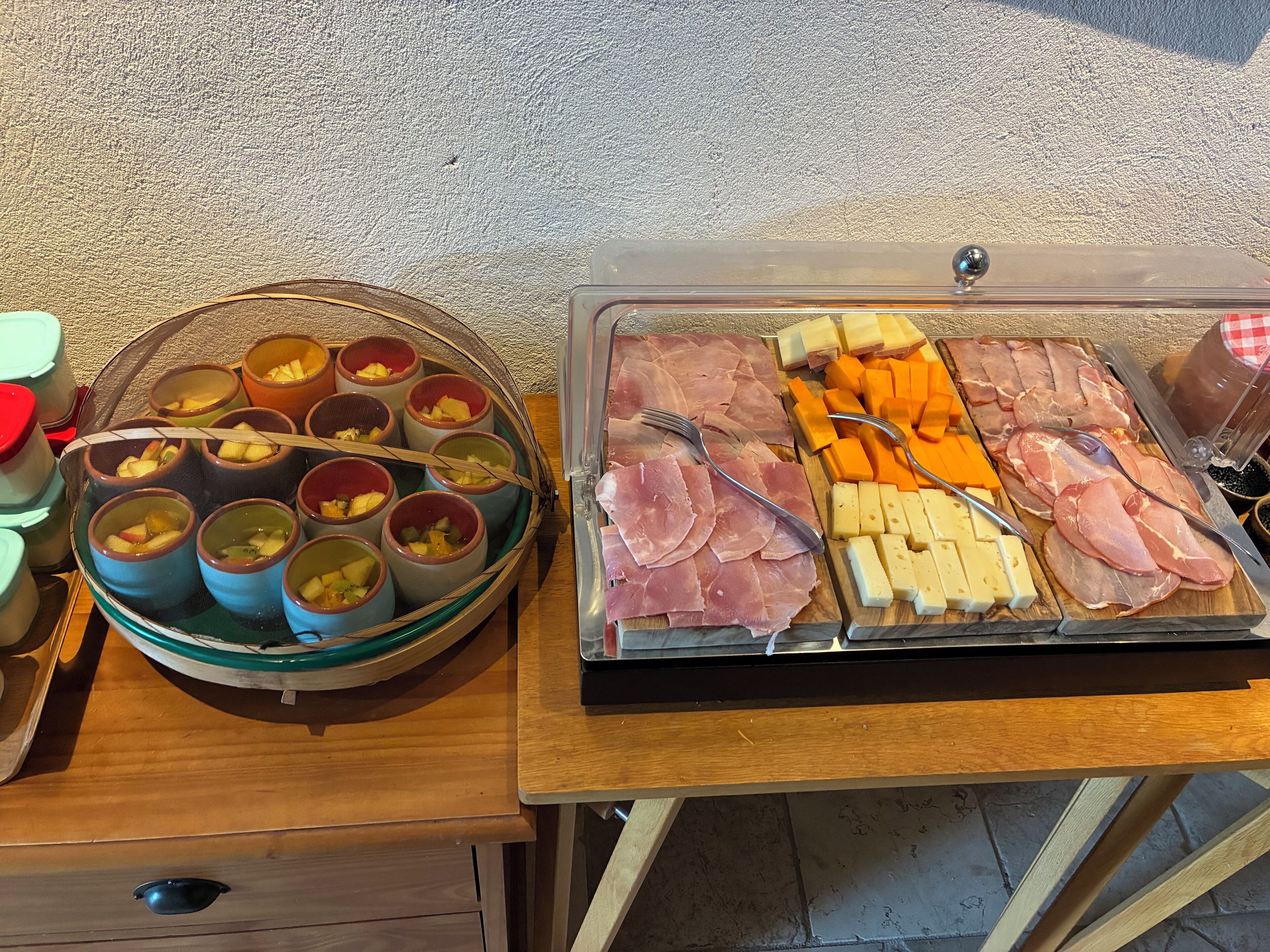 Une table de buffet proposant divers plats, notamment des soupes servies dans des bols, ainsi qu’un assortiment de viandes et de fromages.
