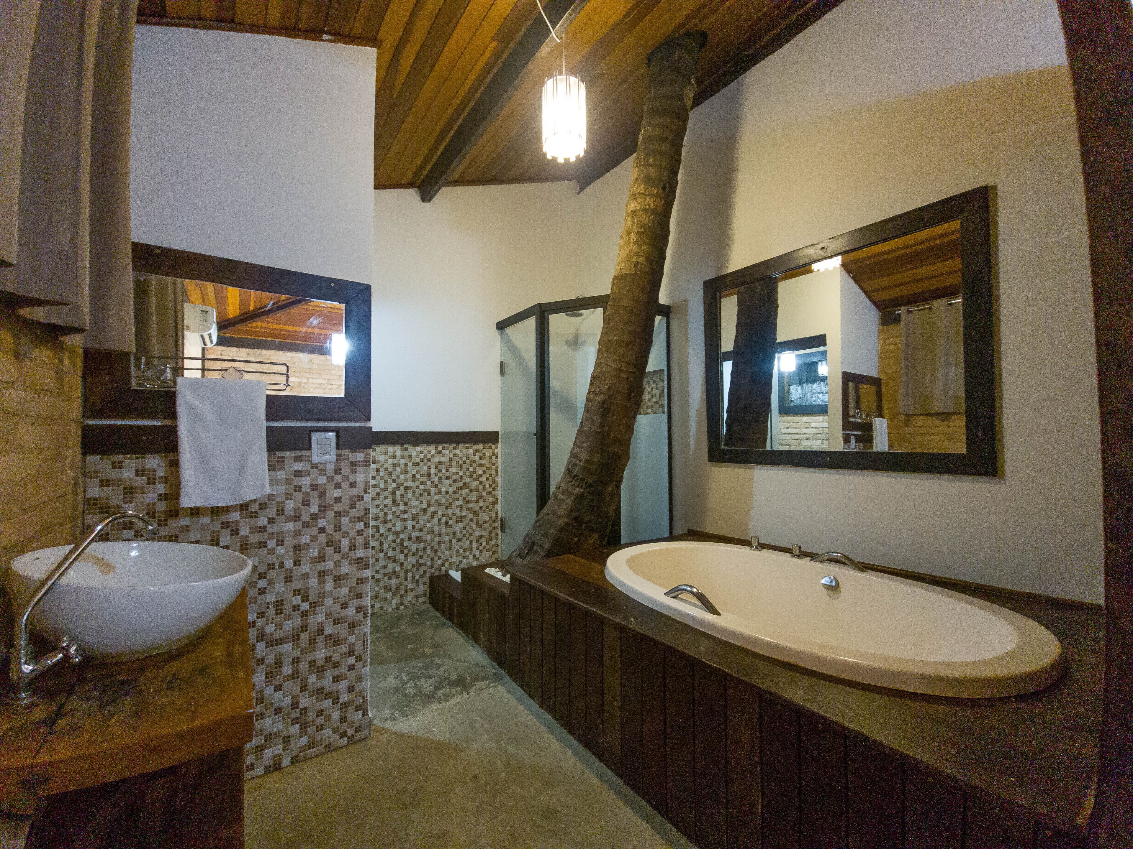 A bathroom with a large mirror, two sinks, a towel hanging on the wall, and a tiled backsplash.