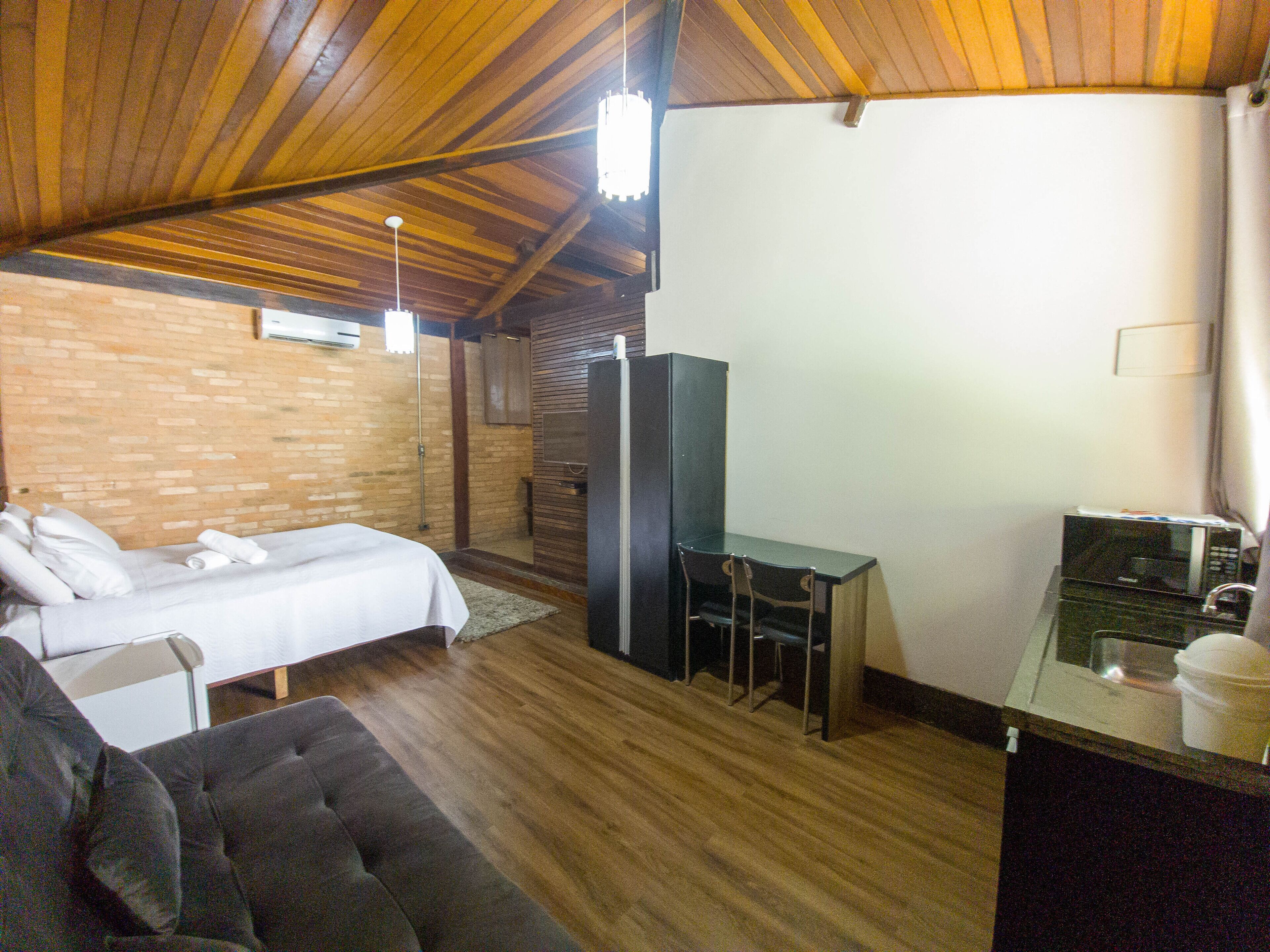 A room with a bed, a desk, a chair, a microwave, and a television.