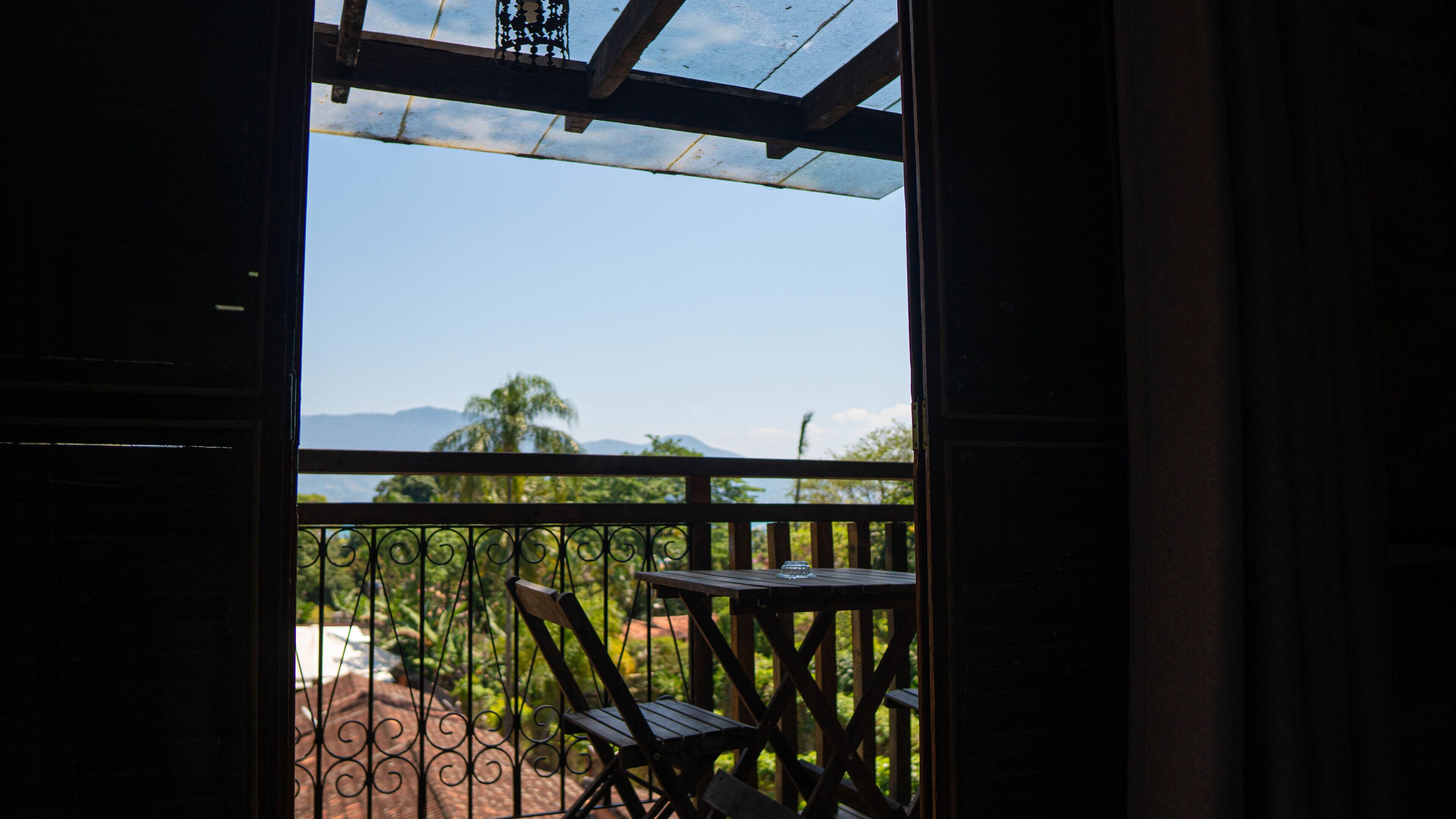 An open balcony with a view of mountains and palm trees.