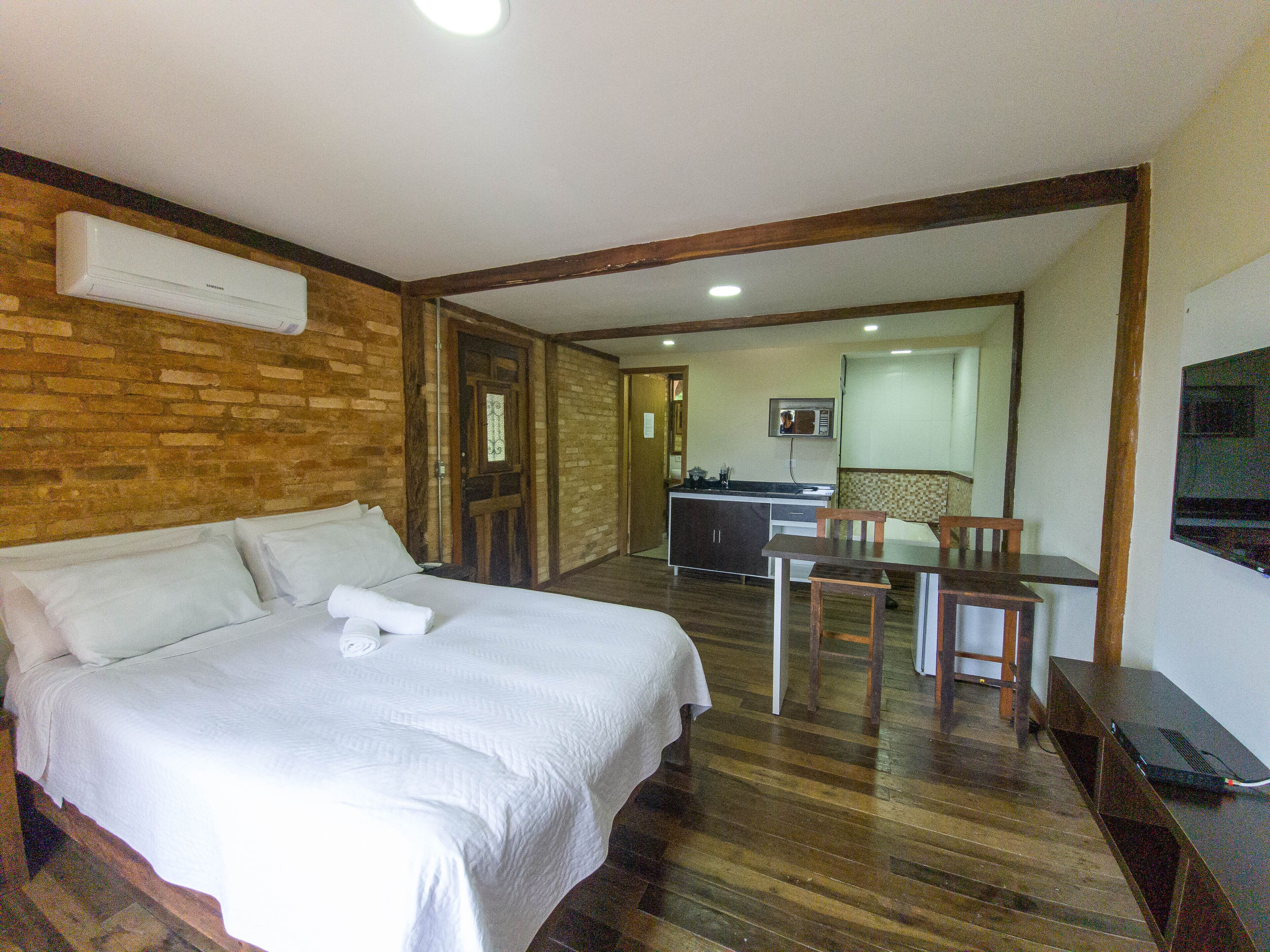 A hotel room with a bed, a desk, and a kitchenette.