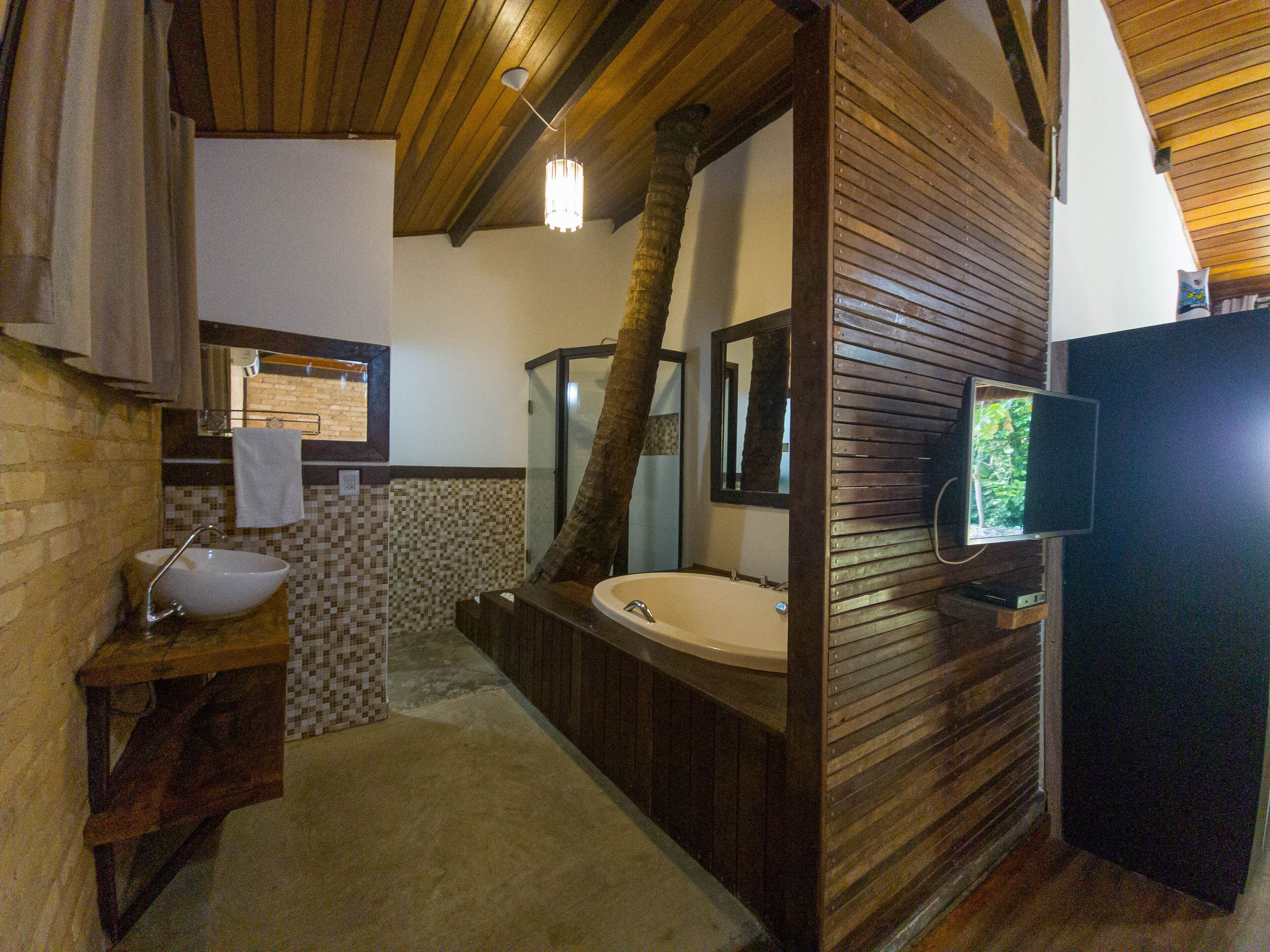 Un baño con tocador de madera, lavamanos, bañera y espejo.