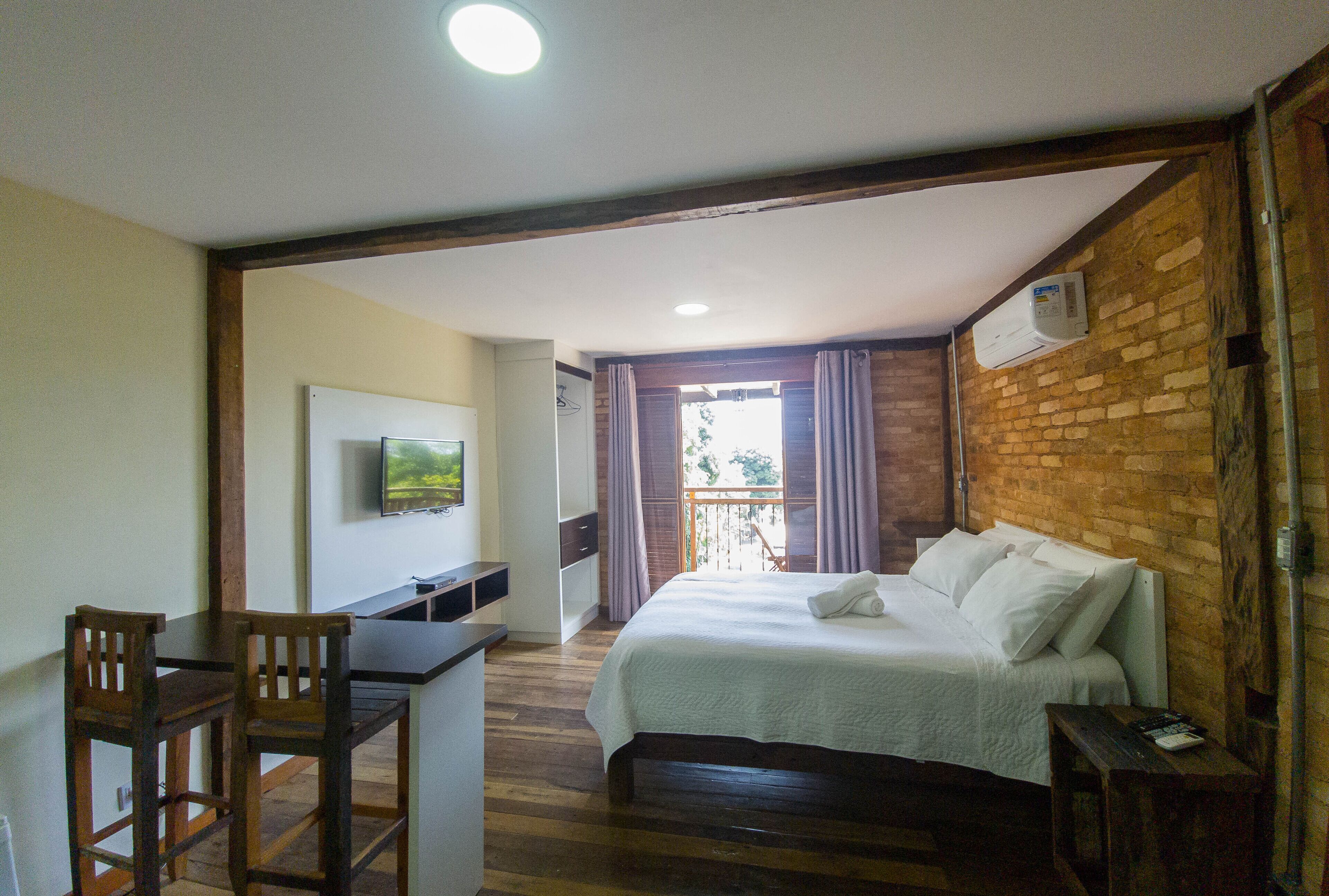A bedroom with a bed, a desk, and a television.