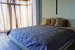 A bedroom with a bed, curtains, and a wall-mounted light fixture.