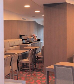 A modern dining area with a sofa, tables, and chairs.