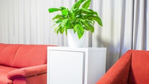 A room with a red sofa, a white side table, and a potted plant. - Tempo Hotel Targu Mures (Tirgu Mures)