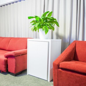 A room with a red sofa, a white side table, and a potted plant. - Tempo Hotel Targu Mures (Tirgu Mures)