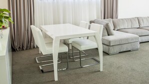 A modern living room with a white table and chairs, a grey sofa, and a large window with curtains. - Tempo Hotel Targu Mures (Tirgu Mures)