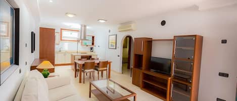 A modern living room with a sofa, coffee table, TV stand, and dining area.
