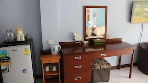 A hotel room with a wooden desk, a refrigerator, a microwave, a kettle, a basket, and a television. - Nap Inn (Ko Pha-ngan)
