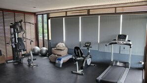 A gym with exercise equipment, including a treadmill, stationary bike, and weight machines. - Nap Inn (Ko Pha-ngan)