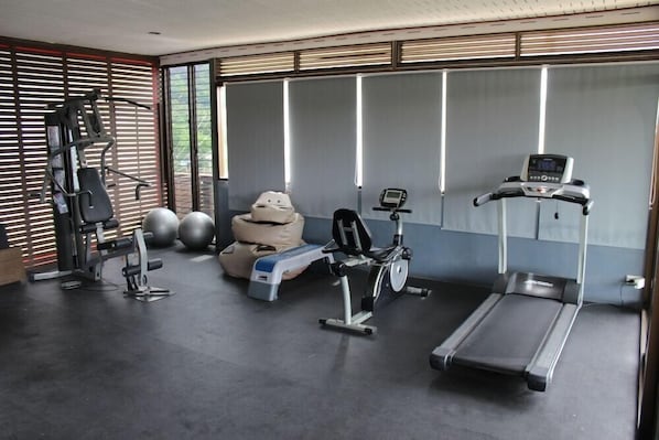 A gym with exercise equipment, including a treadmill, stationary bike, and weight machines. - Nap Inn (Ko Pha-ngan)