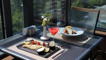 A dining table with a meal, a martini glass, and a vase of flowers.