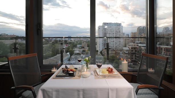Ein Tisch für zwei Personen mit Blick auf die Stadt, Kerzen und eine Blumenvase.