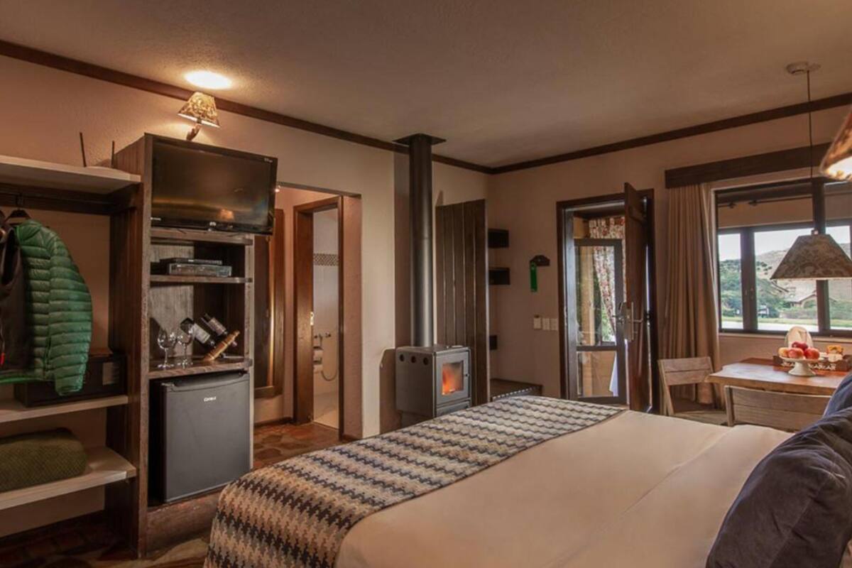 Une chambre d’hôtel comprenant un lit, une petite kitchenette, un coin salon avec une table et des chaises, et une fenêtre donnant sur un paysage agréable.