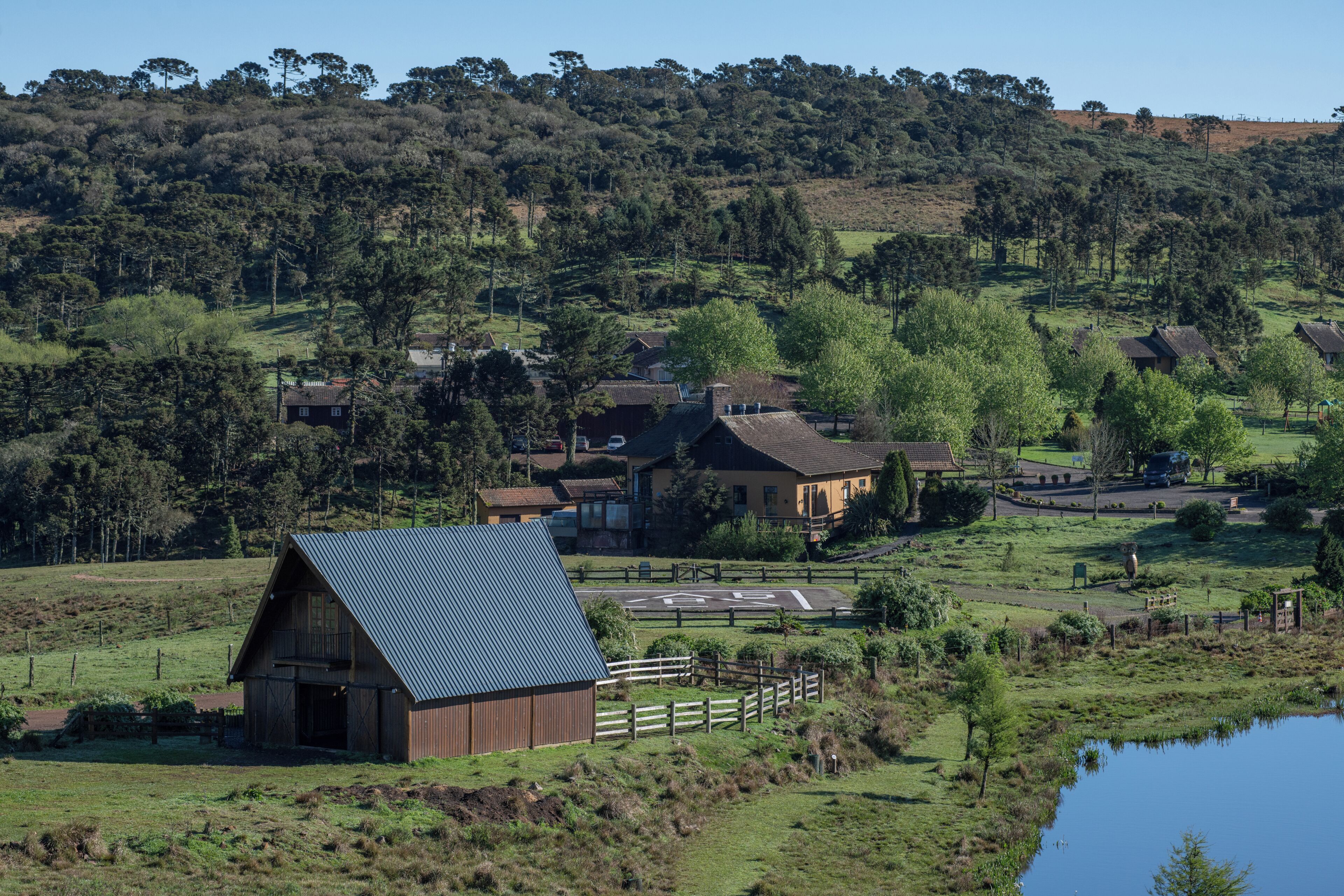 A rural landscape with a barn, houses, and a pond.