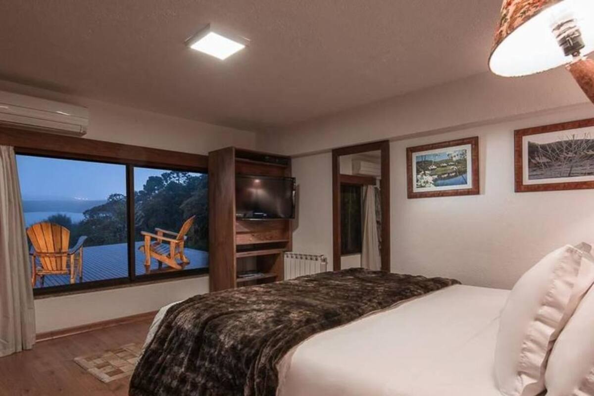 Une chambre avec un grand lit, une télévision, une vue sur l’extérieur et un fauteuil près de la fenêtre.