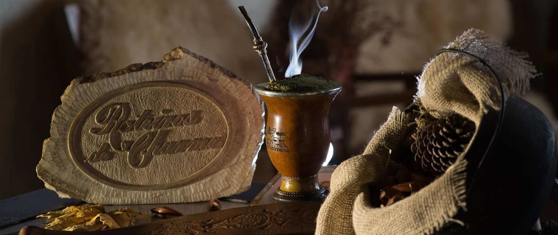Un conjunto tradicional para preparar yerba mate, que incluye una calabaza y un vaso cimbalino, acompañado de una bandeja de metal con un logo.