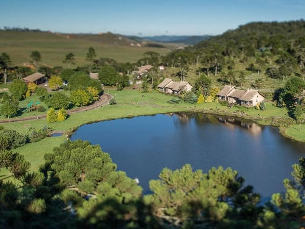 A rural landscape with a pond, houses, and surrounding greenery.