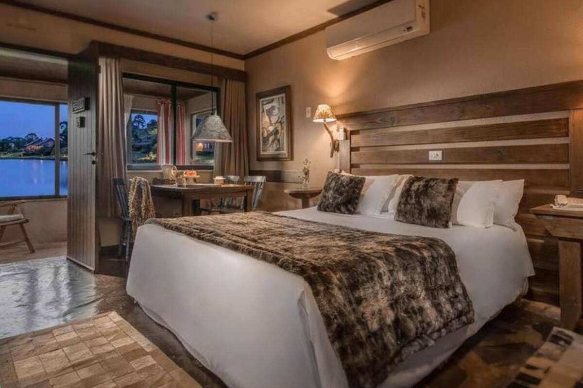 Une chambre spacieuse avec un grand lit, un bureau et une vue sur un plan d’eau.