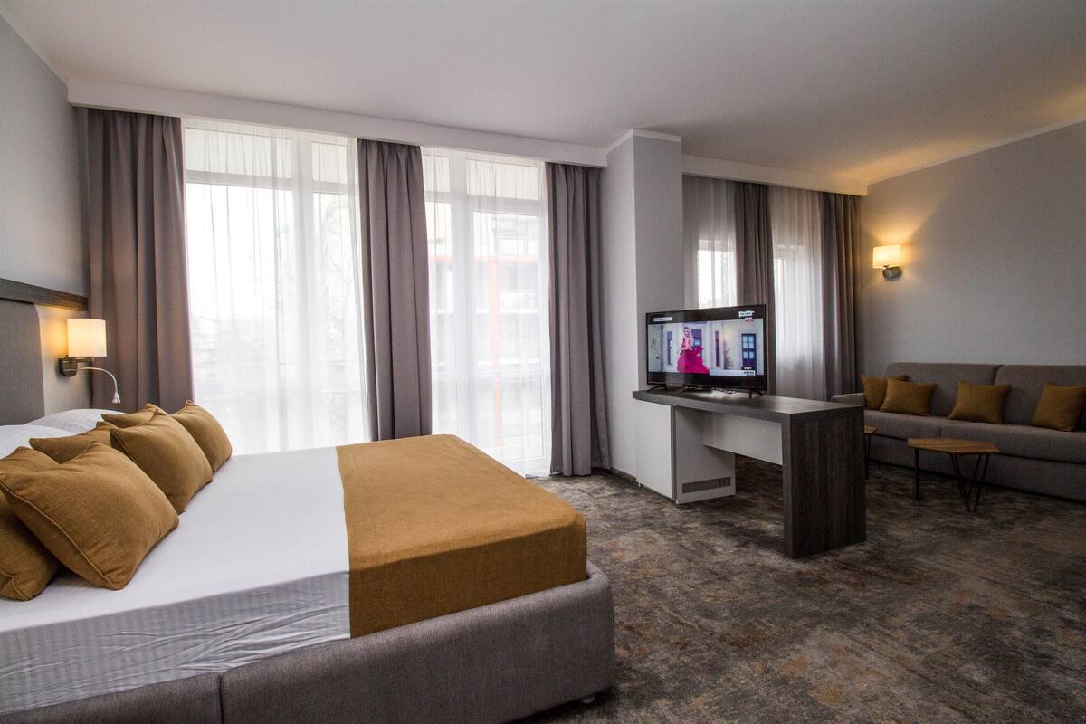 A hotel room with a bed, a desk, a television, and a sofa.