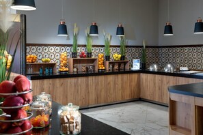 A kitchen with wooden cabinets, a marble countertop, and hanging pendant lights.