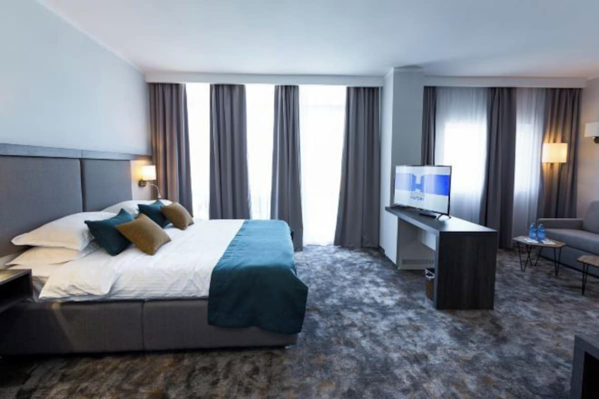Una habitación de hotel con cama, escritorio, televisor y una silla.