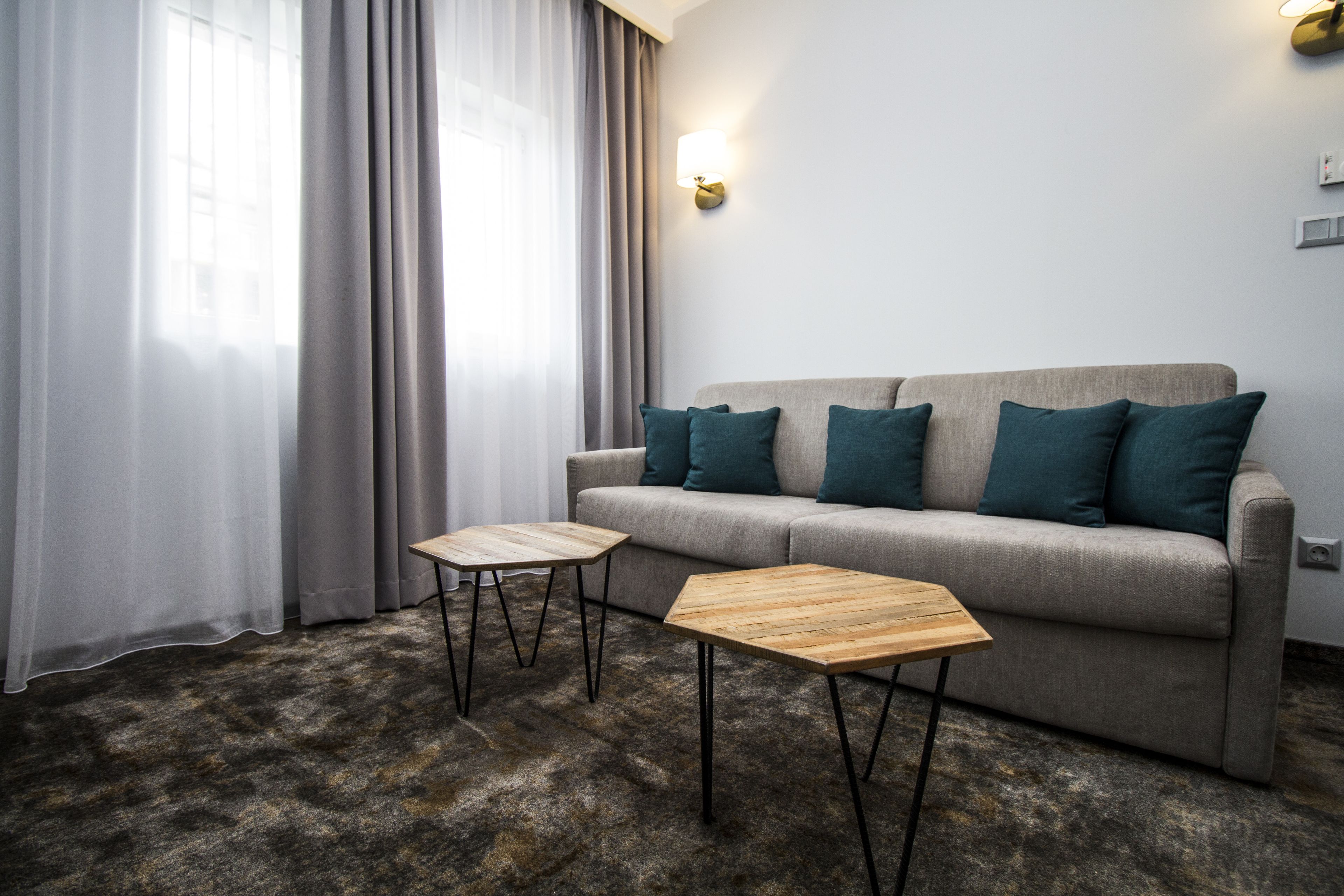 Un soggiorno moderno con un divano grigio, due tavolini di legno e cuscini color acquamarina.