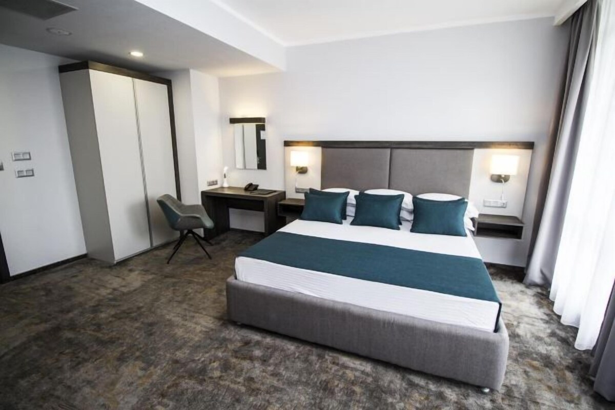 Una habitación de hotel con una cama grande, un escritorio, una silla y un armario.