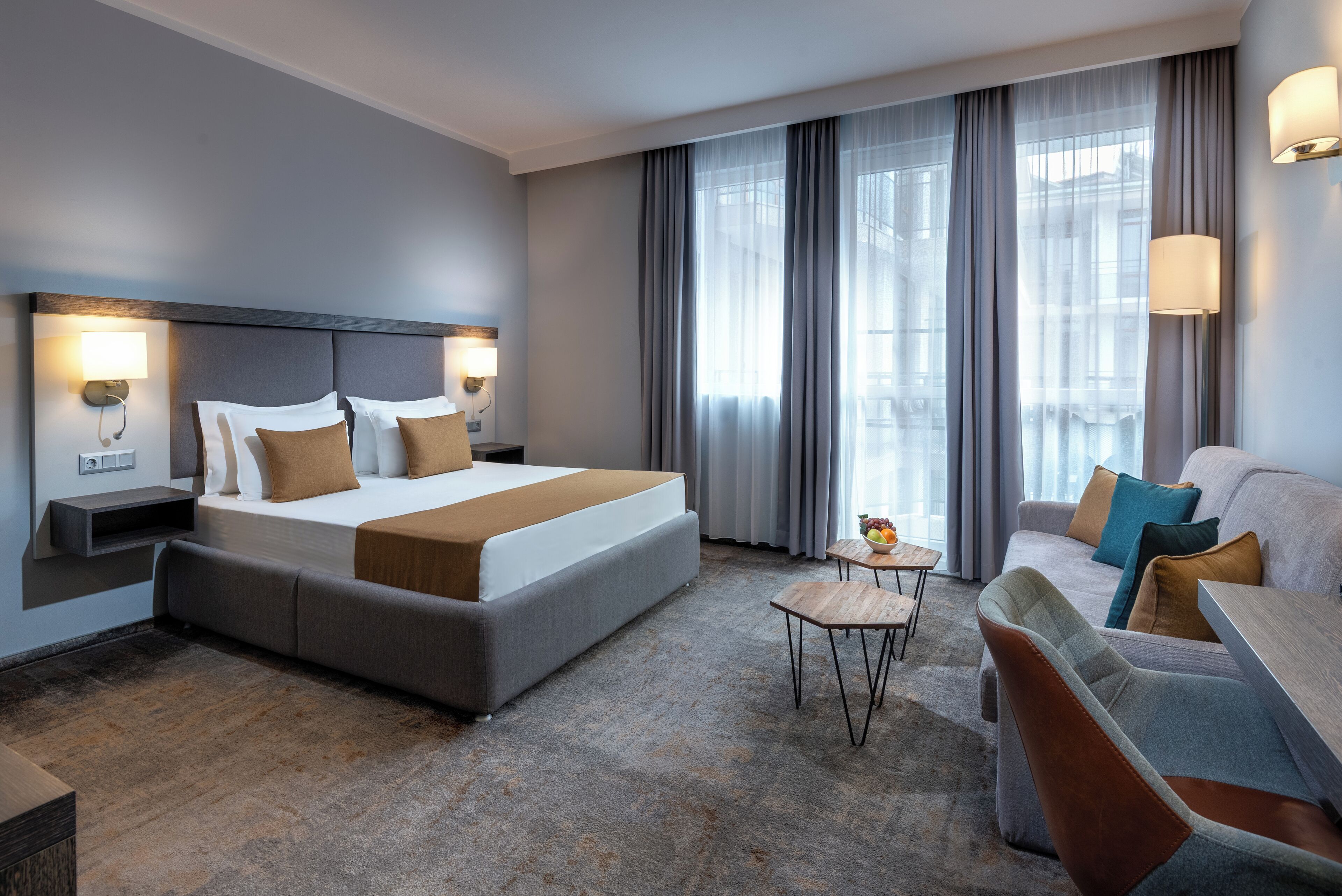 Une chambre d’hôtel moderne avec un grand lit, un canapé, une petite table et un bureau.
