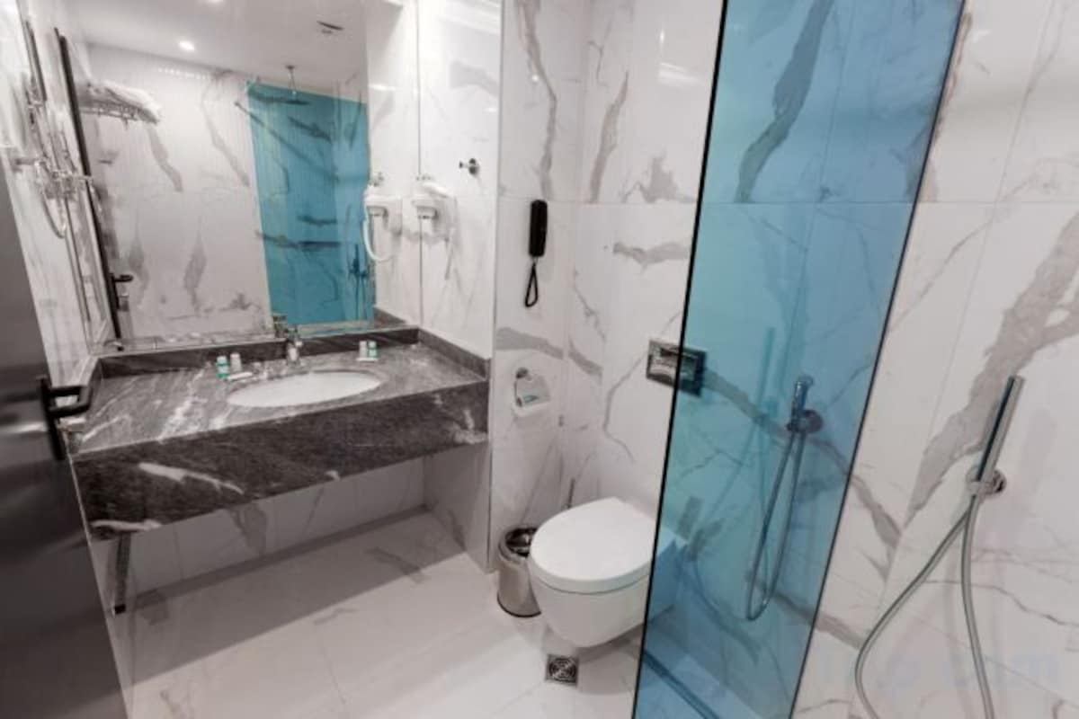 A modern bathroom with a marble sink, a toilet, and a glass shower enclosure.