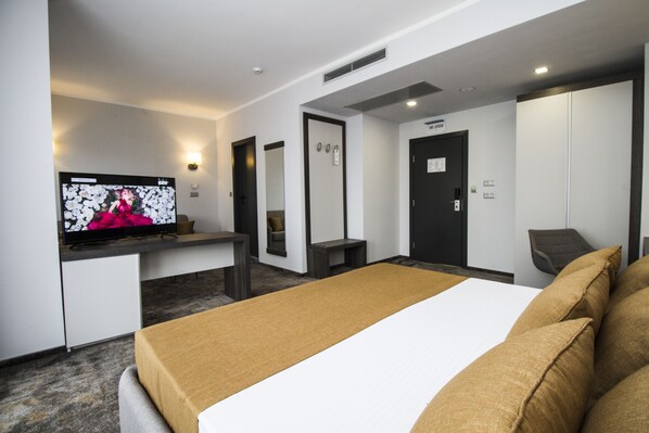 A hotel room with a bed, a television, a desk, and a wardrobe.