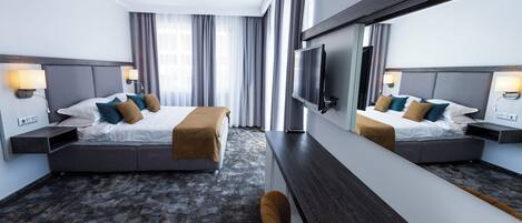 A hotel room with two beds, a large mirror, a TV, and a sofa.