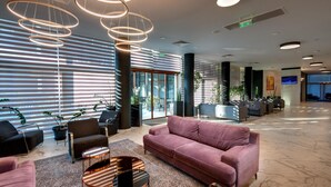 A modern lobby with a plush pink sofa, a round coffee table, and a reception desk. - Best Western Plus Premium Inn (Sunny Beach)