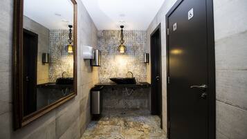 A modern bathroom with two sinks, a mirror, and a door with a handicap symbol.