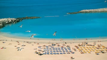 On the beach, white sand, sun-loungers, beach umbrellas