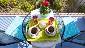 Ein runder Tisch mit einer Tablett, auf dem zwei Tassen Kaffee, ein Teeglas und eine kleine Pflanze mit roten Blüten stehen.