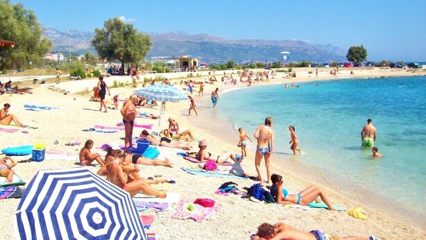 Ein überfüllter Strand mit Menschen, die sich sonnen und schwimmen.
