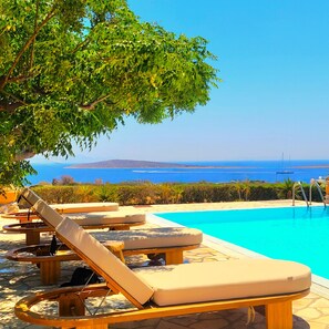 Area piscina con lettini prendisole e vista sul mare.