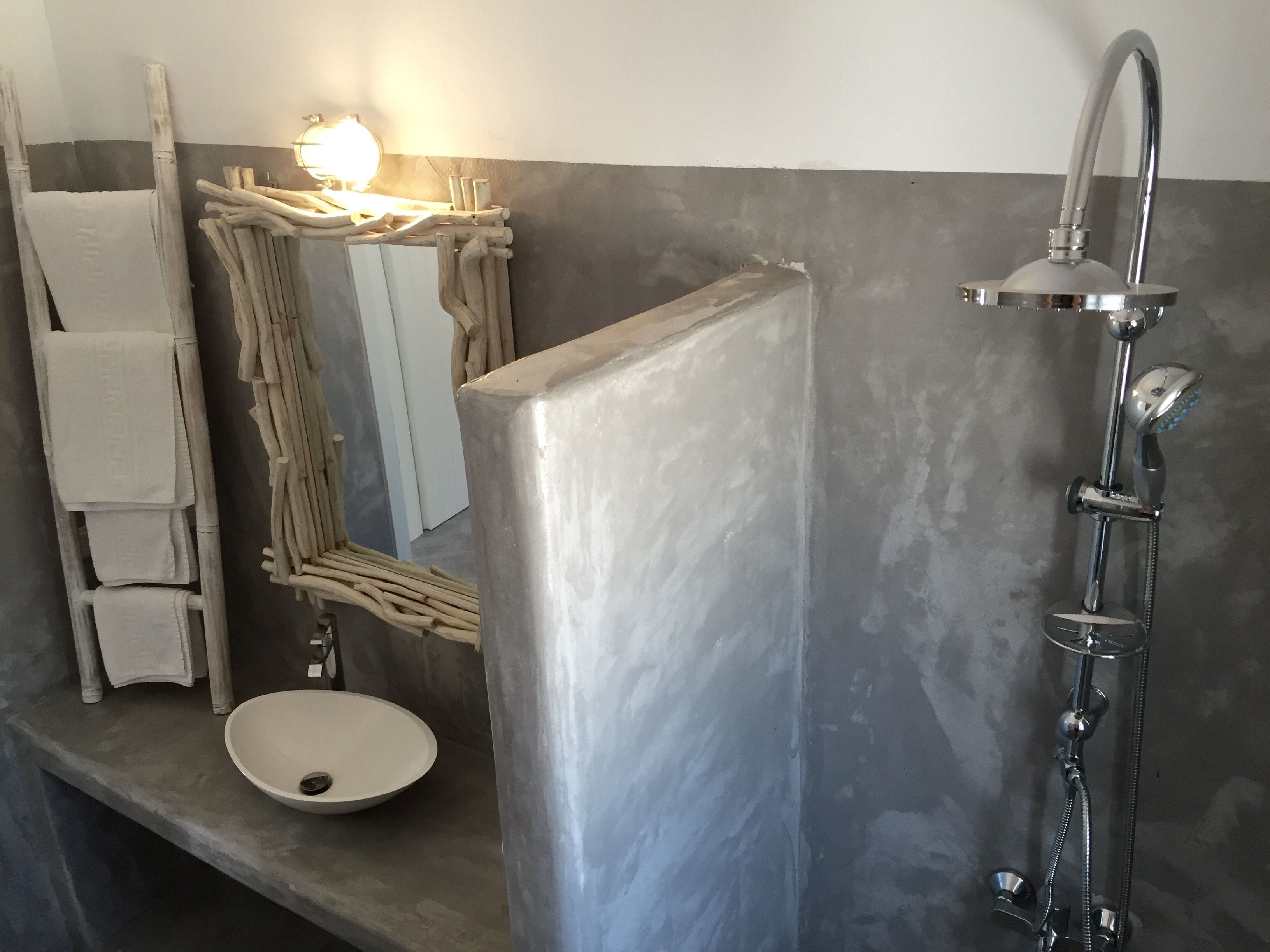 A bathroom with a modern design, featuring a large mirror, a white sink, and a shower with a handheld showerhead.