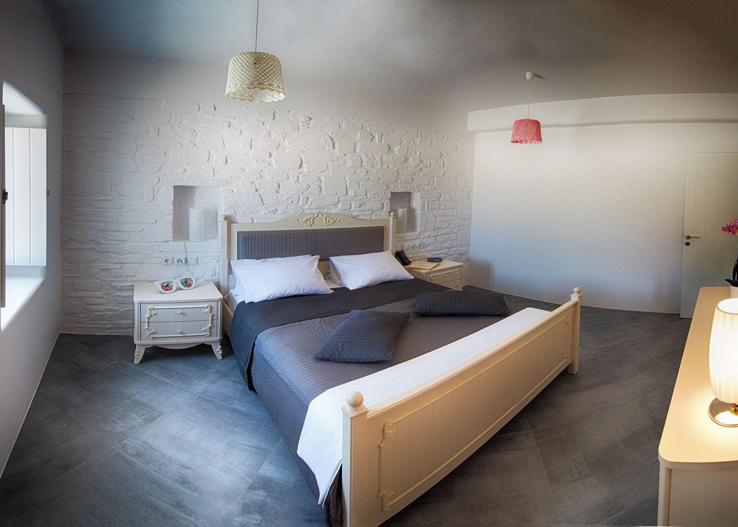 A bedroom with a bed, bedside tables, a lamp, and a wall with a textured pattern.
