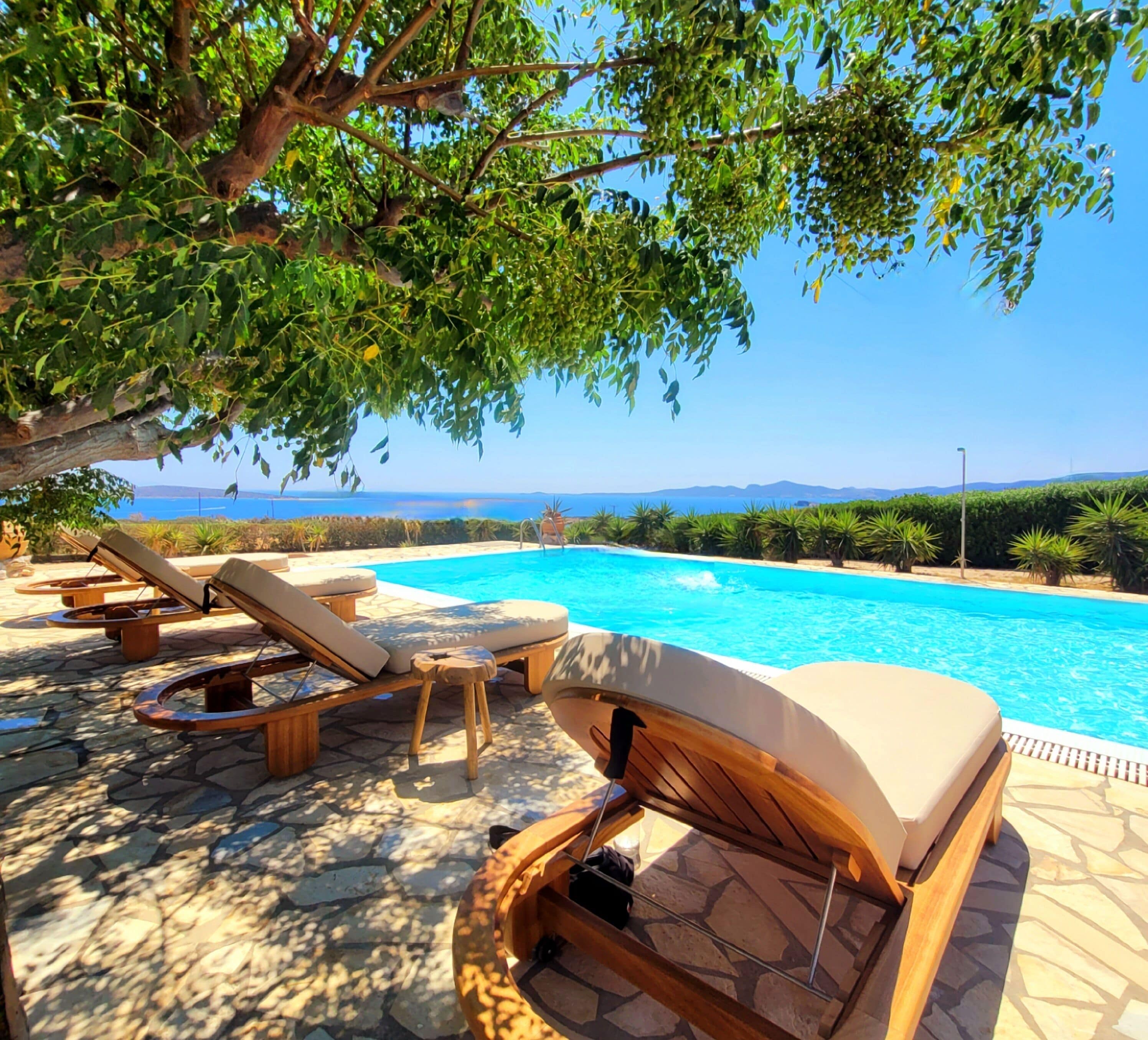A poolside area with lounge chairs and a clear view of the sea.