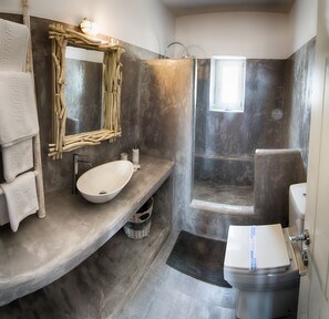 A modern bathroom with a large oval sink, a wooden-framed mirror, a shower with a glass door, and a toilet.