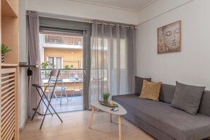 A modern living room with a grey sofa, a small white table, and a balcony with a chair and plants.