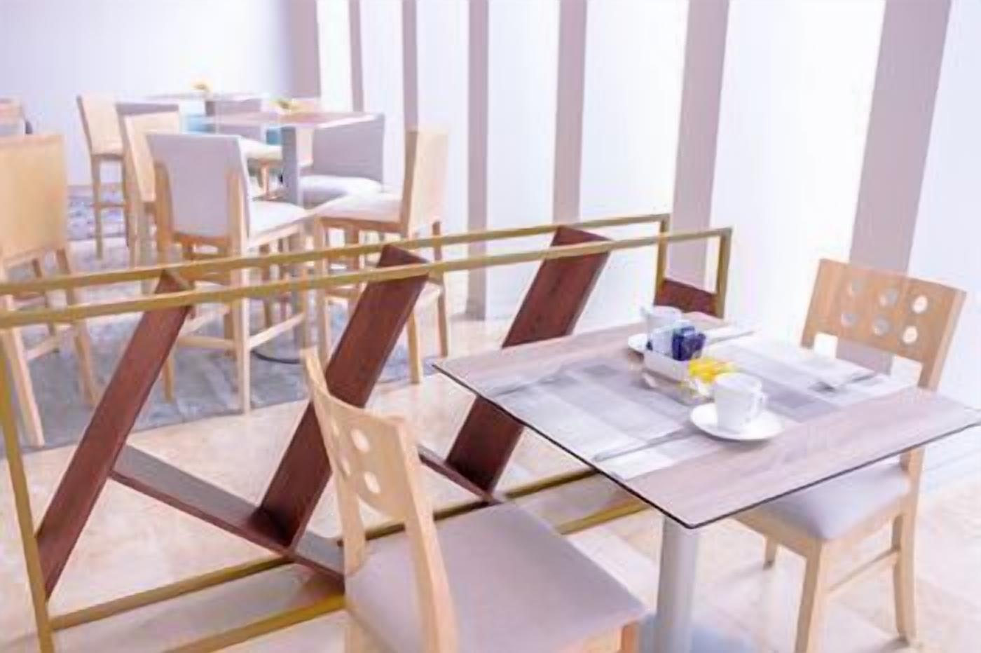 Een moderne eetruimte met houten stoelen en tafels, een glazen scheiding en een strak, minimalistisch design.
