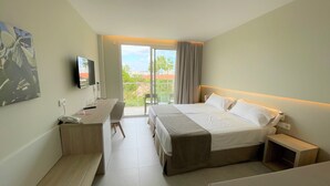 A hotel room with a bed, a desk, a chair, a TV, and a balcony with a view. - Hotel Garbí Cala Millor (Sant Llorenc des Cardassar)
