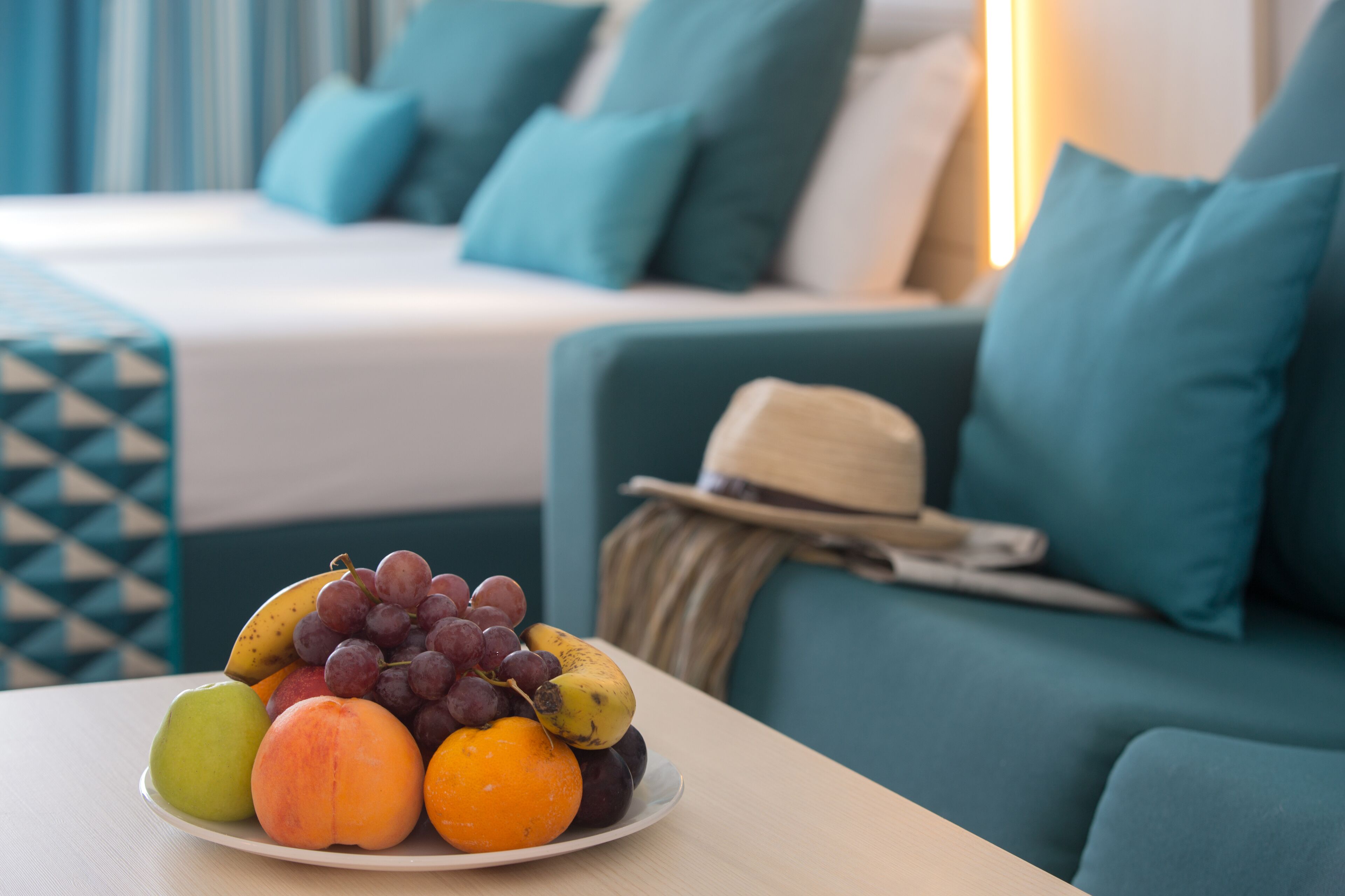 A fruit plate on a table in a room with a bed and teal-colored furniture.