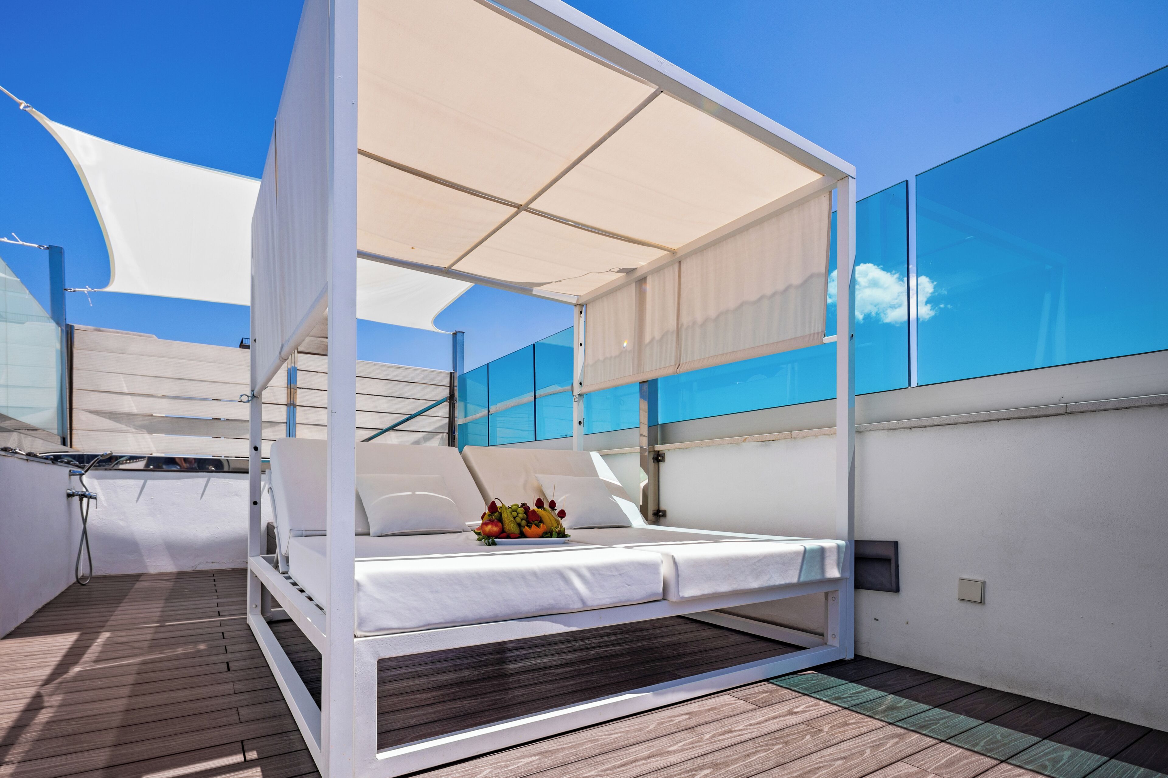 A modern outdoor bedroom with a canopy, a bed, and a fruit basket.